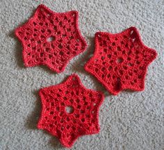 three red crocheted coasters sitting on top of a white carpeted floor