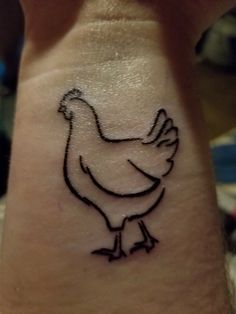 a hen tattoo is on the wrist of a person's left arm, which has a black outline of a chicken on it