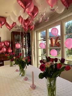 vases filled with flowers on top of a table next to balloons in the shape of hearts