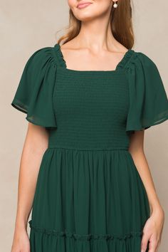 The perfect bridesmaids dress has entered the chat. Introducing our Ellie Dress in Emerald Chiffon! Made from luxurious chiffon fabric, this women's dress features a square neckline with ruffle detailing at the shoulder for a touch of elegance. The 1/2 length flutter sleeves add a playful touch, while the pull-over style with a smocked bodice make it nursing friendly and maternity friendly. The midi-length skirt and full lining add volume and movement to this must-have fall dress. Green Flutter Sleeve Dress With Ruffle Hem, Flowy Short Sleeve Maternity Dress, Green Short Sleeve Maternity Dress For Summer, Green Short Sleeve Maternity Dress, Maternity Short Sleeve Dress With Ruffle Hem, Green Bubble, City Woman, Perfect Bridesmaid Dress, Fall Dress