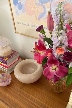 a vase filled with flowers sitting on top of a wooden table next to a stack of books