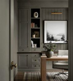 an office with gray walls and wooden flooring, built in cabinets and desks