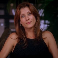 a woman in a black dress looking at the camera with an intense look on her face