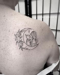 the back of a woman's shoulder with a bear and flower tattoo on it