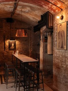 the interior of a bar with wooden tables and stools in an old brick building