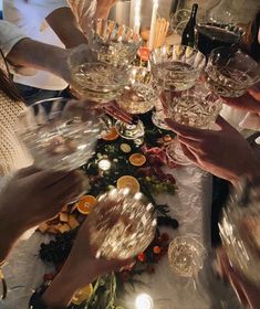 many people are holding wine glasses and toasting at a table with candles on it