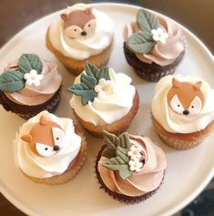 cupcakes with frosting and decorations on a white plate in the shape of animals