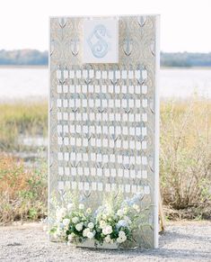 a white and blue wedding ceremony sign with flowers