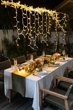 a long table is set with dinnerware and lite - up lights in the background