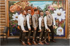 a group of men standing next to each other in front of a wall with flowers on it