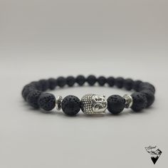 Bring a touch of serenity and sophistication to your outfit.The 8mm Buddha Head Lava Bead Bracelet is the versatile accessory you need. This handcrafted bracelet is custom made to fit your wrist perfectly. The number of beads varies depending on the size requested (approx. 25 beads for an 18cm wrist) The Buddha Head Lava Bead Bracelet is an elegant and spiritual accessory that will bring a touch of serenity and sophistication to your outfit. The black beads, made of lava stone, are recognizable by their porous and rough texture, adding a natural dimension to the bracelet. The small silver or gold metal Buddha head is finely detailed, adding a spiritual dimension to the bracelet. It will be placed between two small pearls matching the color of the Buddha's head (Silver or gold). The overall Hand-strung Lava Stone Bracelets, Adjustable Lava Stone Bracelet For Meditation, Adjustable Lava Stone Stretch Bracelet For Meditation, Meditation Bracelets With Natural Lava Stones, Spiritual Lava Stone Bracelets With 8mm Beads, Spiritual Lava Stone Beaded Bracelets With 8mm Beads, Minimalist Round Beads Bracelets For Meditation, Casual Bracelets For Meditation With 8mm Beads, Casual Bracelets With 8mm Beads For Meditation