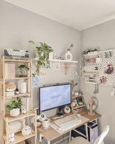 a desk with a computer on top of it next to a shelf filled with plants