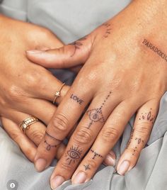 two people holding hands with tattoos on their fingers