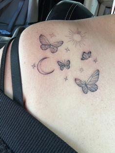 the back of a woman's shoulder with butterflies flying around