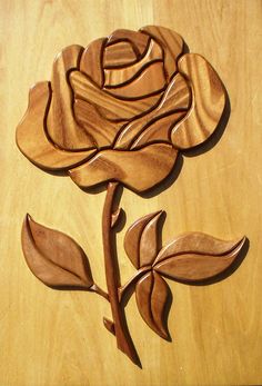 a wooden rose on a table with leaves and stems carved into the wood, ready to be used as a wall decoration