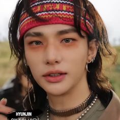 a young man with long hair wearing a red and white knitted headband is looking at the camera