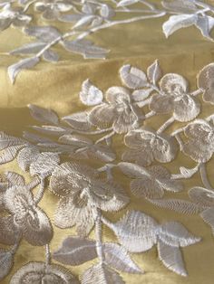 an embroidered gold cloth with white flowers and leaves on the bottom, along with silver thread