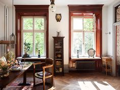 an old fashioned living room with wood floors and large windows on the wall, along with antique furniture