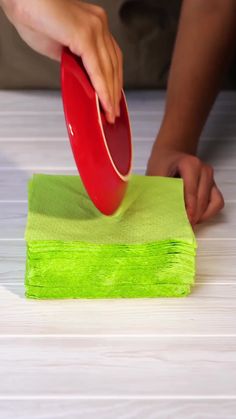 a person is using a red disc to clean a table top with green cloths