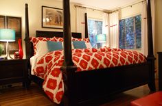 a bed with red and white comforter in a bedroom next to two lamps on either side of the bed