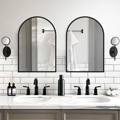 two bathroom sinks with mirrors above them and soap dispensers on the counter