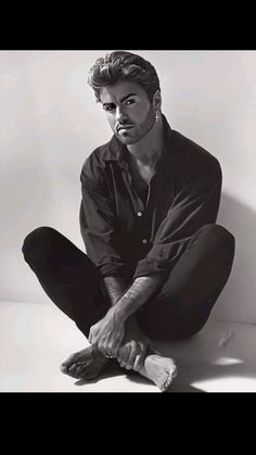 a black and white photo of a man sitting on the floor with his feet crossed