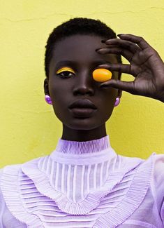 a woman holding two oranges up to her eye