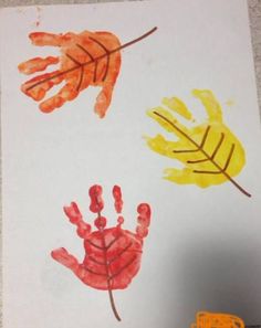 a child's handprint with three different colored leaves on it and a toy truck in the background