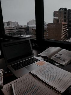 an open laptop computer sitting on top of a desk next to a book and notebook