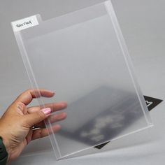 a person's hand holding up a clear plastic sheet