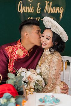 a bride and groom kissing each other in front of a sign that says annie & huang