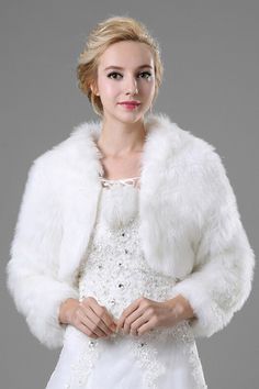 a woman in a white wedding dress and fur coat with beading on the shoulders