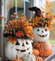 two pumpkins decorated with flowers and leaves on a window sill