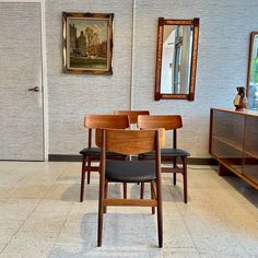 a dining room table and chairs in front of a painting on the wall with an open door