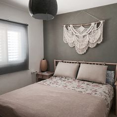 a bedroom with a bed, nightstands and hanging decorations on the wall above it