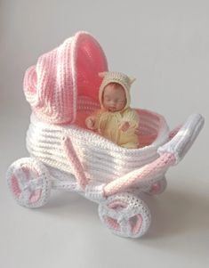 a baby in a pink and white crocheted carriage with a hat on it