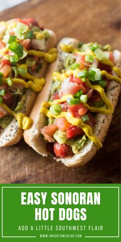 two hot dogs with toppings sitting on top of a wooden cutting board