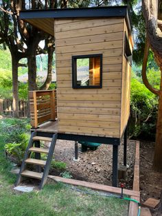 a small wooden house sitting on top of a lush green field next to a tree