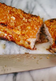 two pieces of meat sitting on top of a counter next to a knife