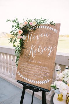 a wooden sign with flowers and greenery on it