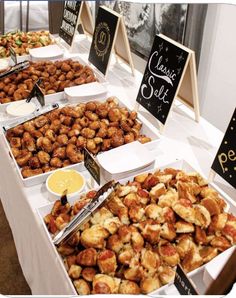 an assortment of different types of food on display at a buffet table with chalkboard signs