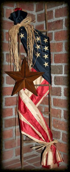 an american flag hanging on the side of a brick wall with stars and ribbons attached to it