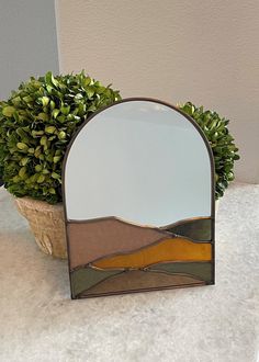 a mirror sitting on top of a counter next to a potted plant