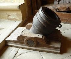 an old cast iron pot sitting on top of a wooden stand in front of a door