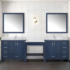 two sinks and mirrors in a bathroom with white tiles on the walls, blue cabinets