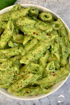 a white bowl filled with green guacamole on top of a table next to a napkin