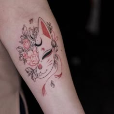 a woman's arm with a cat and flowers tattoo on the left side of her arm