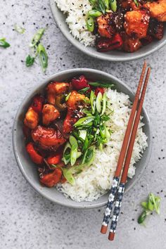 two bowls filled with rice and vegetables next to chopsticks on a table top