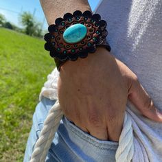 "Brown leather bracelet that has a paisley filigree. It is adorned with turquoise cabochon concho and a hand painted leather rosette. Measures 7.75\" to 8.25\" with two snaps for adjustment." Western Style Turquoise Leather Bracelets, Turquoise Leather Concho Bracelets, Adjustable Turquoise Cuff Bracelet With Concho, Adjustable Turquoise Leather Bracelet With Concho, Western Style Turquoise Bracelet, Hand Tooled, Turquoise Leather Concho Jewelry, Adjustable Hand-tooled Turquoise Cuff Bracelet, Adjustable Hand Tooled Turquoise Cuff Bracelet, Adjustable Turquoise Hand Tooled Cuff Bracelet