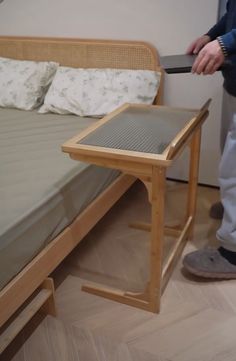 a person standing next to a bed with a wooden frame and foot rest on it